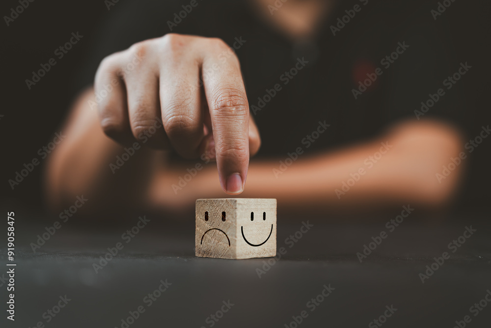 © Nirusmee - Man hand points on a wooden cube with happy smile face on bright side and unhappy face on dark side of wooden block cube for a positive mindset selection. Emotional state and mental health concept. © Nirusmee - Man hand points on a wooden cube with happy smile face on bright side and unhappy face on dark side of wooden block cube for a positive mindset selection. Emotional state and mental health concept.