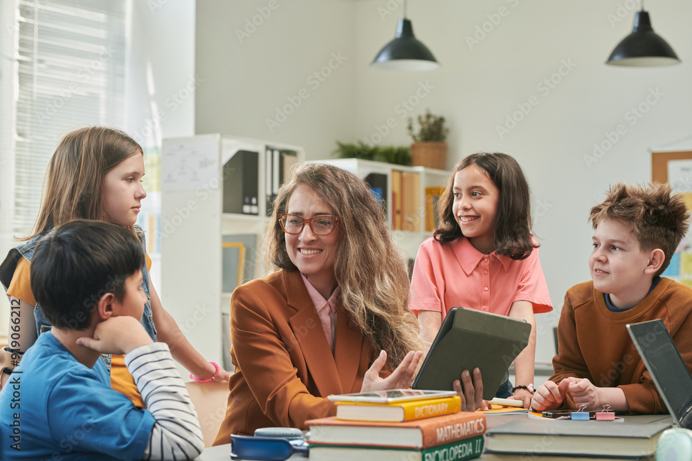 Portrait of smiling female teacher enjoying class with diverse group of young children and using tablet Portrait of smiling female teacher enjoying class with diverse group of young children and using tablet