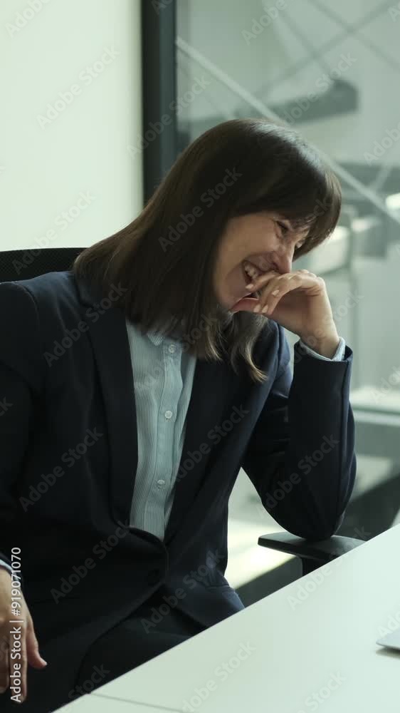 Cheerful Caucasian middle aged female employee talking in online video call and laughing while spending work break. Vertical video. Cheerful Caucasian middle aged female employee talking in online video call and laughing while spending work break. Vertical video.