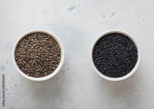 Bowls with dry raw black and green lentils seeds on kitchen table.Macro.