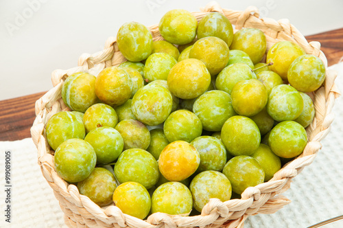 sweet yellow plums in a basket on the table. ripe plums of the Renclod variety

