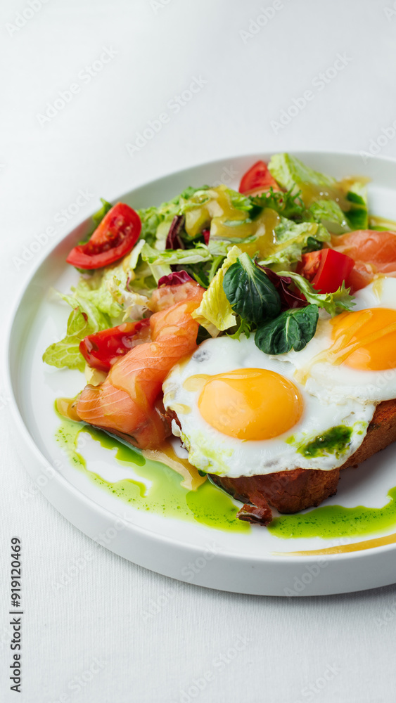 Breakfast, two eggs served on toasted bread with a green herb sauce. Accompanied fresh salad, cherry tomatoes, and smoked salmon slices, all elegantly presented on a white plate and white background Breakfast, two eggs served on toasted bread with a green herb sauce. Accompanied fresh salad, cherry tomatoes, and smoked salmon slices, all elegantly presented on a white plate and white background