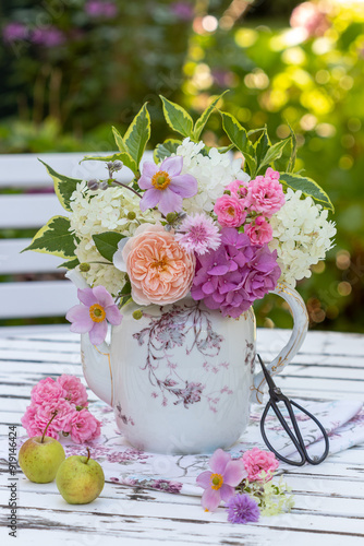 romantischer Blumenstrauß mit Rosen, Hortensienblüten, Herbst-Anemone und Spindelstrauch-Zweigen in einer vintage Kaffeekanne photo