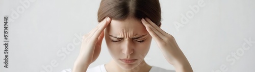 Young woman experiencing headache, holding hands to head in pain on white background, close-up.