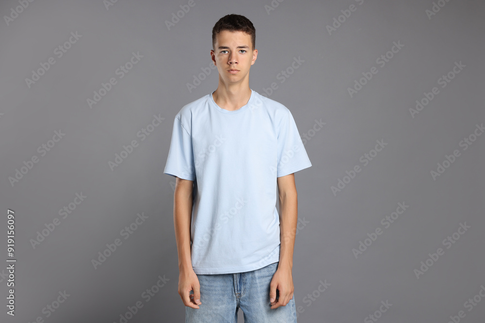 Fototapeta premium Teenage boy wearing light blue t-shirt on grey background