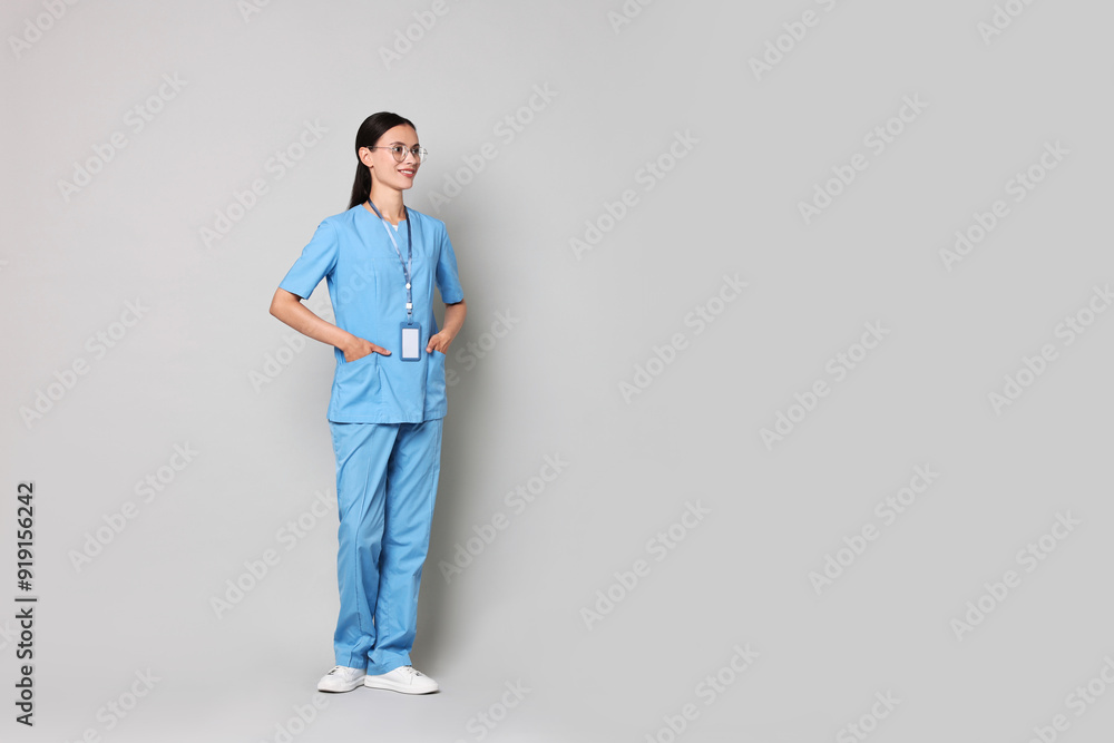Smiling nurse in uniform on grey background. Space for text Smiling nurse in uniform on grey background. Space for text