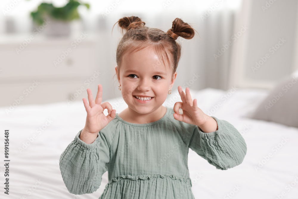 Portrait of happy little girl showing OK gesture in bedroom Portrait of happy little girl showing OK gesture in bedroom