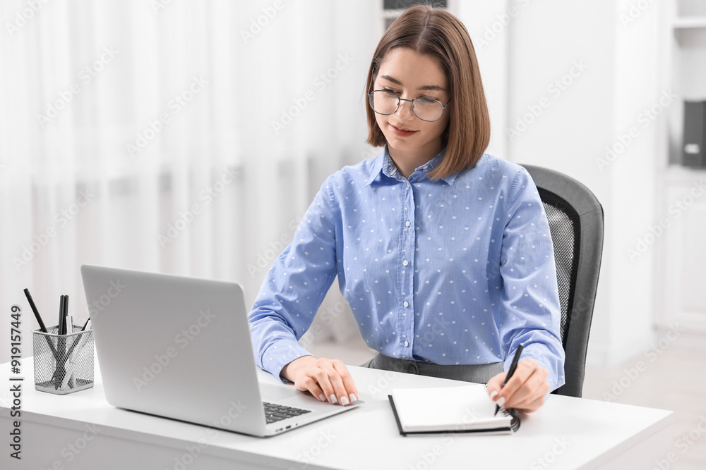 Teenager taking notes while working with laptop at home. Remote job Teenager taking notes while working with laptop at home. Remote job