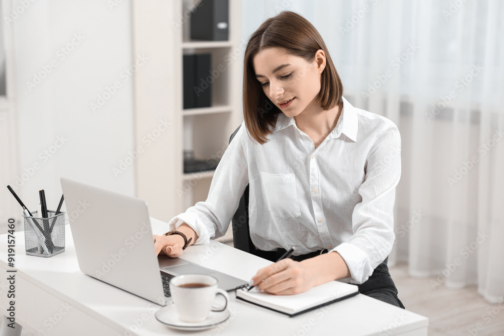Teenager taking notes while working with laptop at home. Remote job Teenager taking notes while working with laptop at home. Remote job