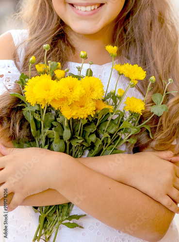 Cute Caucasian girl with a smile and a bouquet of yellow chrysanthemums. Happiness concept