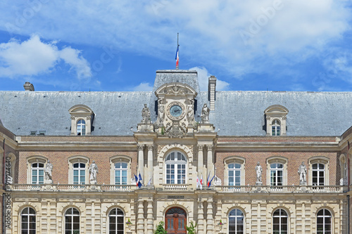 City hall in Amiens with clock, sculptures and flags and blue sky with white clouds, France photo