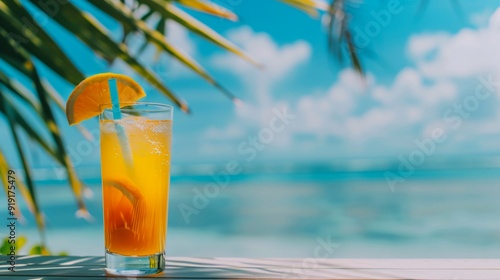 A delicious and refreshing orange tropical cocktail in a transparent glass against the background of the blue ocean and palm leaves. The concept of leisure and travel. Copy Space