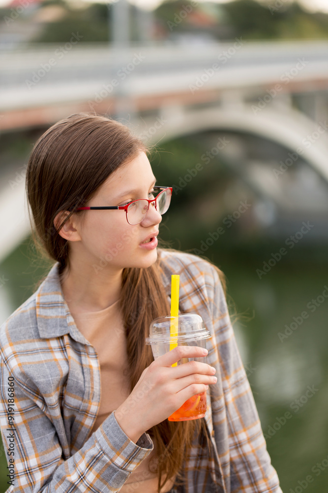 A teenage girl drinks bubble tea on a walk near the river