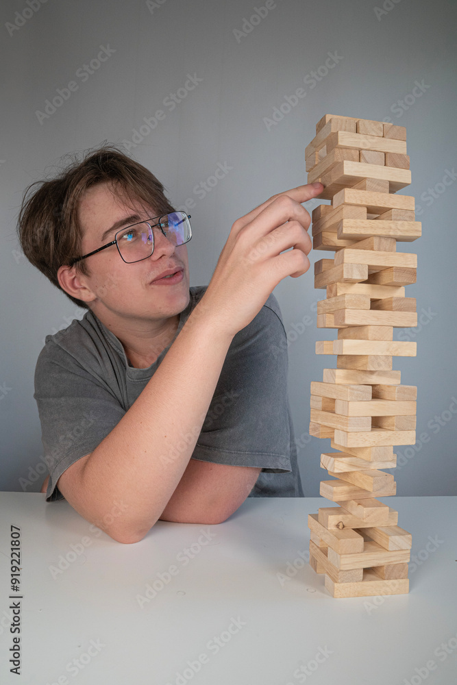 skupiona osoba wyciągająca jedną ręką klocki Jenga