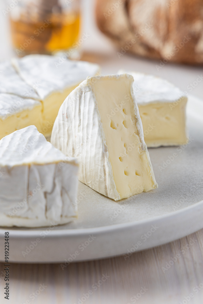 Camembert Cheese Wheel on a Light Plate with a Slice Removed, Soft Cheese Texture Camembert Cheese Wheel on a Light Plate with a Slice Removed, Soft Cheese Texture