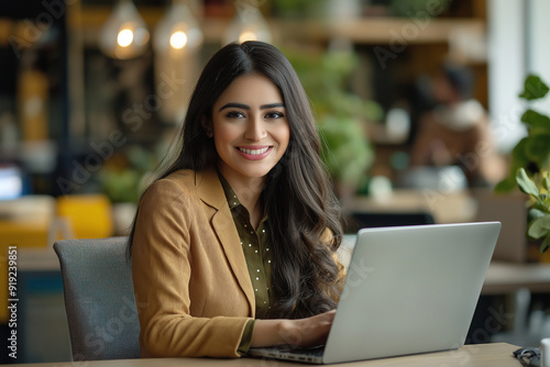 Obraz na płótnie Happy latin hispanic young business woman working on laptop computer in company office. Smiling Indian entrepreneur manager businesswoman using pc for communication, learning at workplace w salonie