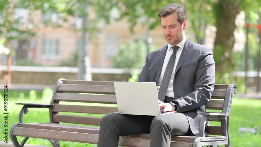 Middle Aged Businessman Working on Laptop while Sitting Outdoor on Bench Middle Aged Businessman Working on Laptop while Sitting Outdoor on Bench