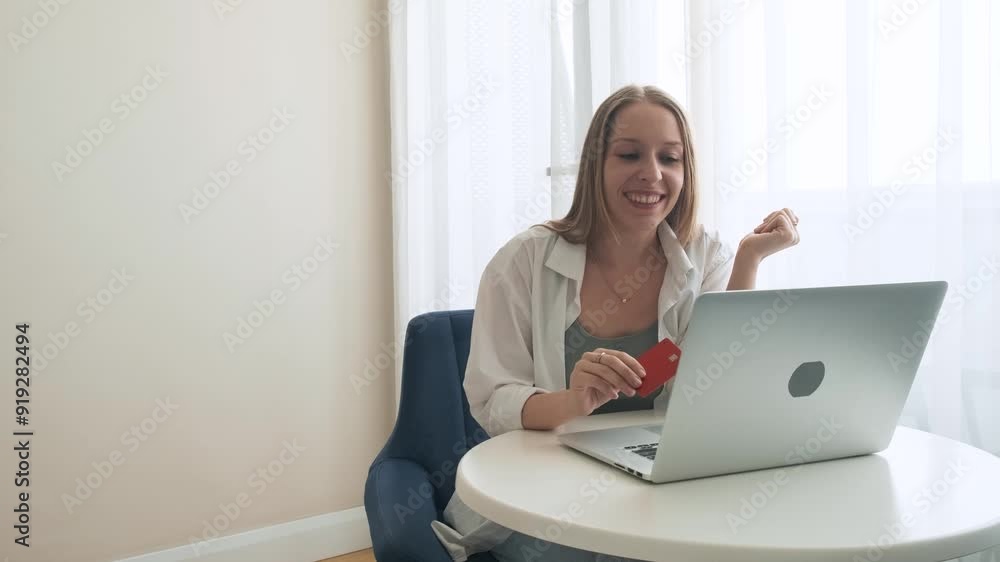 Happy woman celebrates successful online shopping with credit card while her male partner looks concerned about family budget. Couple with different emotions. Compulsive buying disorder concept Happy woman celebrates successful online shopping with credit card while her male partner looks concerned about family budget. Couple with different emotions. Compulsive buying disorder concept