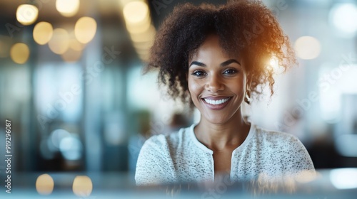 A woman with a warm smile stands in the office light, creating a pleasant and inviting atmosphere. Her genuine joy reflects positivity and contentment within the workplace. photo