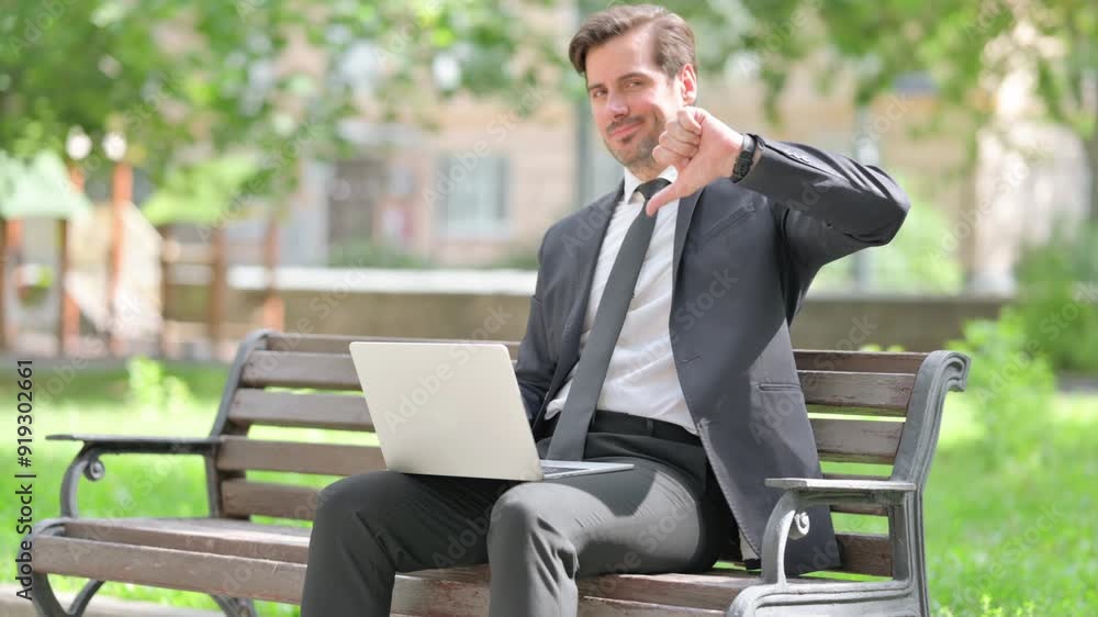 Thumbs Down by Middle Aged Businessman Using Laptop Outdoor on Bench Thumbs Down by Middle Aged Businessman Using Laptop Outdoor on Bench