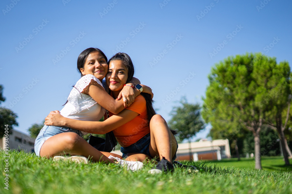 Fototapeta premium Two Latina sisters from Peru hugging in an outdoor park