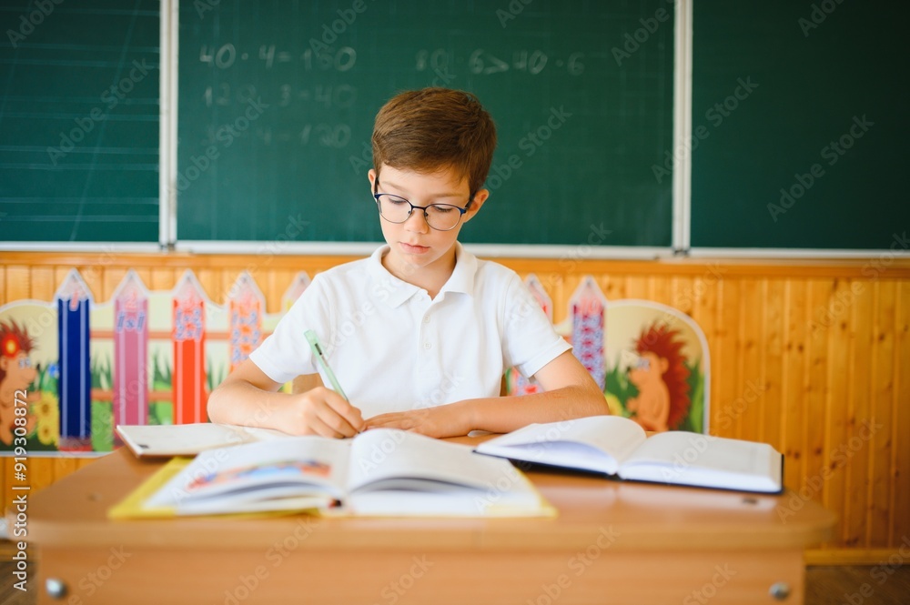 Happy schoolboy sitting at desk, classroom Happy schoolboy sitting at desk, classroom