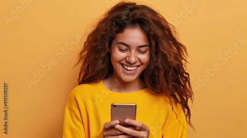 Cheerful young woman using smartphone on pink background.