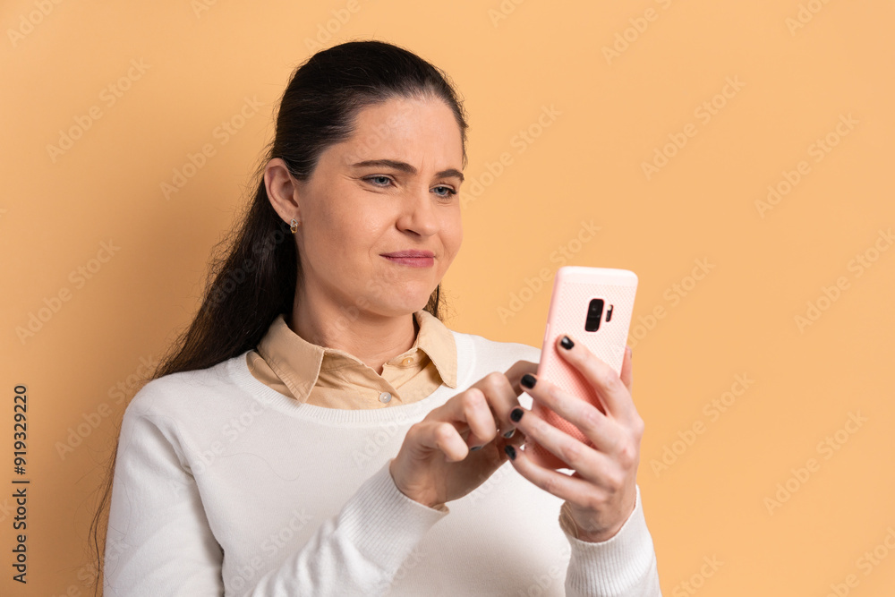 puzzled caucasian woman watching video and photos on mobile smartphone in all beige colors. communication, app, connection concept. puzzled caucasian woman watching video and photos on mobile smartphone in all beige colors. communication, app, connection concept.