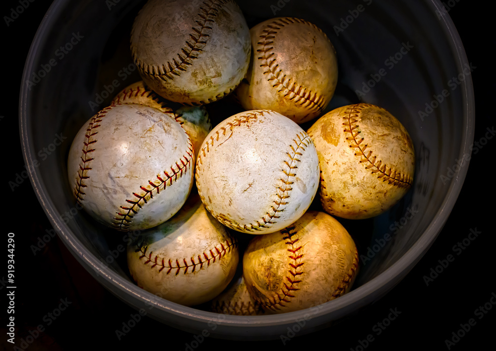 Old used white leather covered softballs in a bucket for sale at an antique shop in Upstate NY. Used sport equipment at a thrift shop. Old used white leather covered softballs in a bucket for sale at an antique shop in Upstate NY. Used sport equipment at a thrift shop.