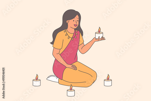Indian woman in traditional dress holds candles sitting on knees and doing ritual at Diwali festival