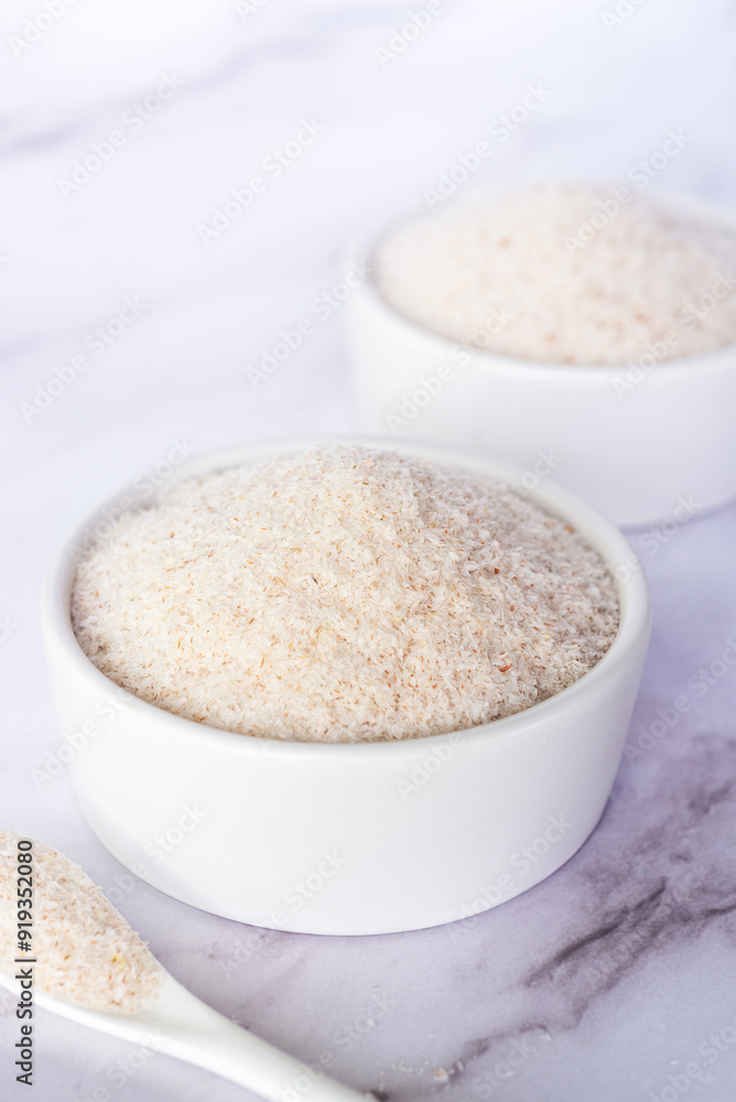 spyllium husk in white ceramic bowl on white marble table background. spyllium husk in white ceramic bowl on white marble table background.