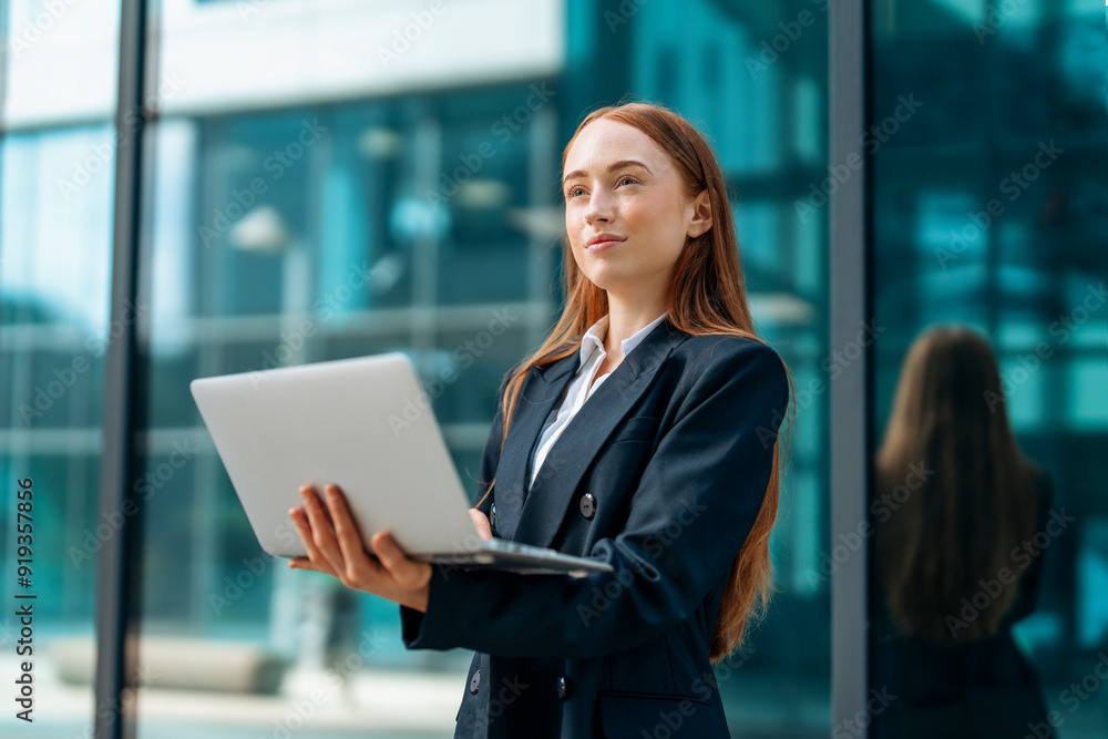 Confident businesswoman working outdoors with laptop in modern urban setting during sunny afternoon Confident businesswoman working outdoors with laptop in modern urban setting during sunny afternoon