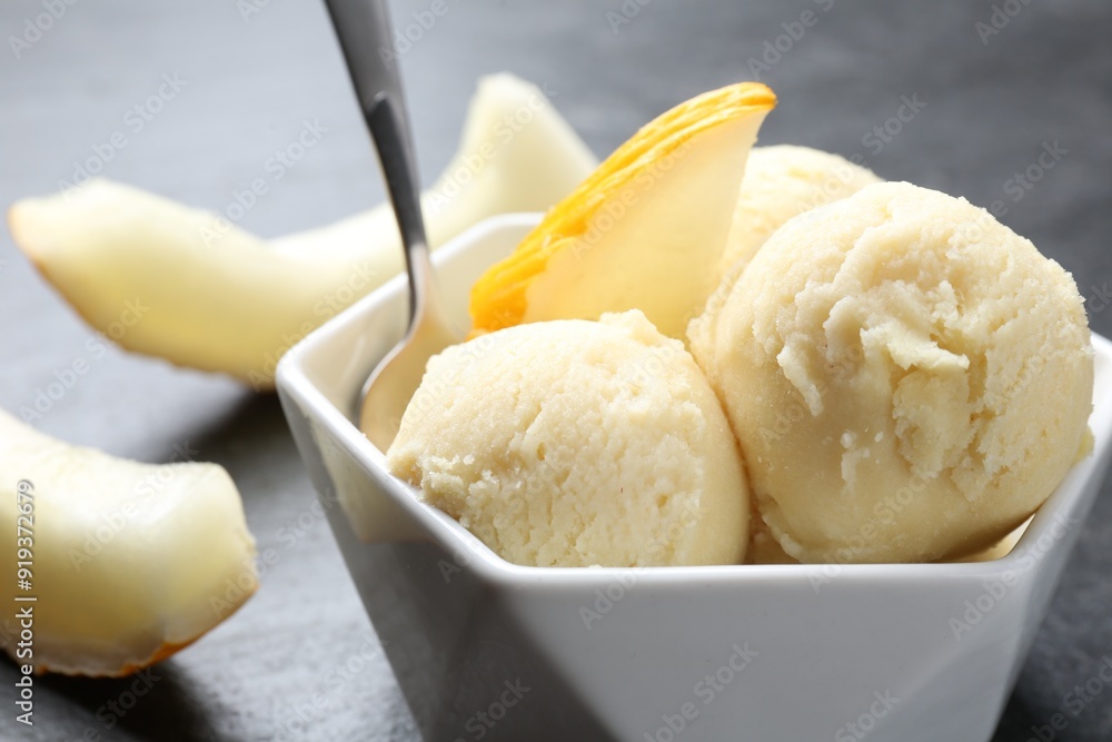 Scoops of tasty melon sorbet with fresh fruit and spoon in bowl on grey table, closeup Scoops of tasty melon sorbet with fresh fruit and spoon in bowl on grey table, closeup