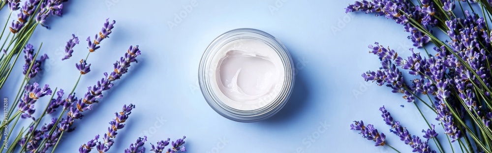 Light blue background with lavender flowers on top of cosmetic products Light blue background with lavender flowers on top of cosmetic products