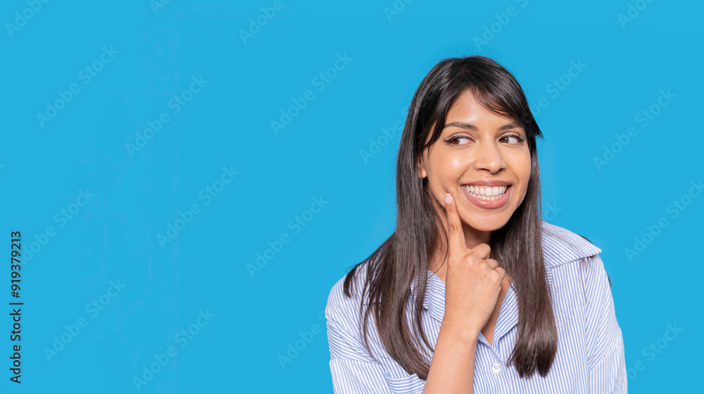 Smiling Woman With Long Hair in Striped Shirt Against Bright Blue Background Smiling Woman With Long Hair in Striped Shirt Against Bright Blue Background