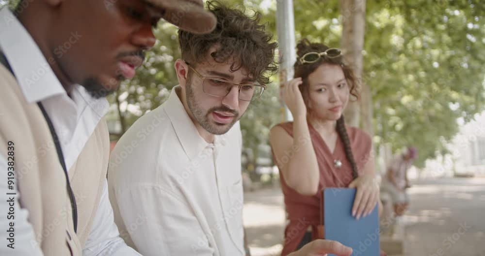A diverse group of young professionals is collaborating on a project outdoors. They are deeply engaged in discussion and teamwork, demonstrating their focus and commitment in the open-air setting. A diverse group of young professionals is collaborating on a project outdoors. They are deeply engaged in discussion and teamwork, demonstrating their focus and commitment in the open-air setting.