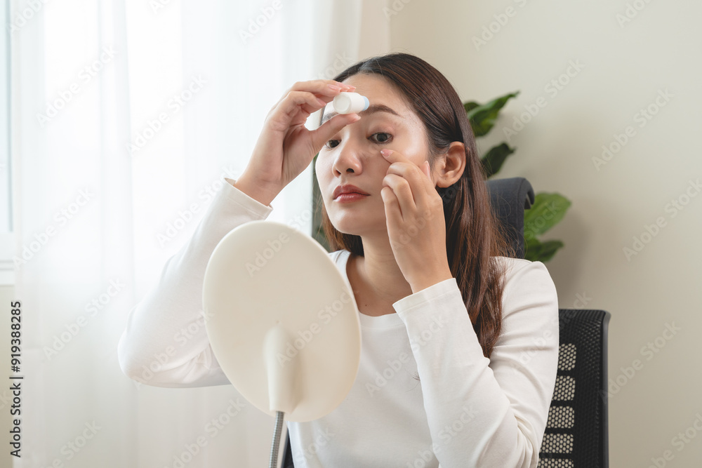 asian young woman using medical eye drops to treat dry eye and irritation asian young woman using medical eye drops to treat dry eye and irritation