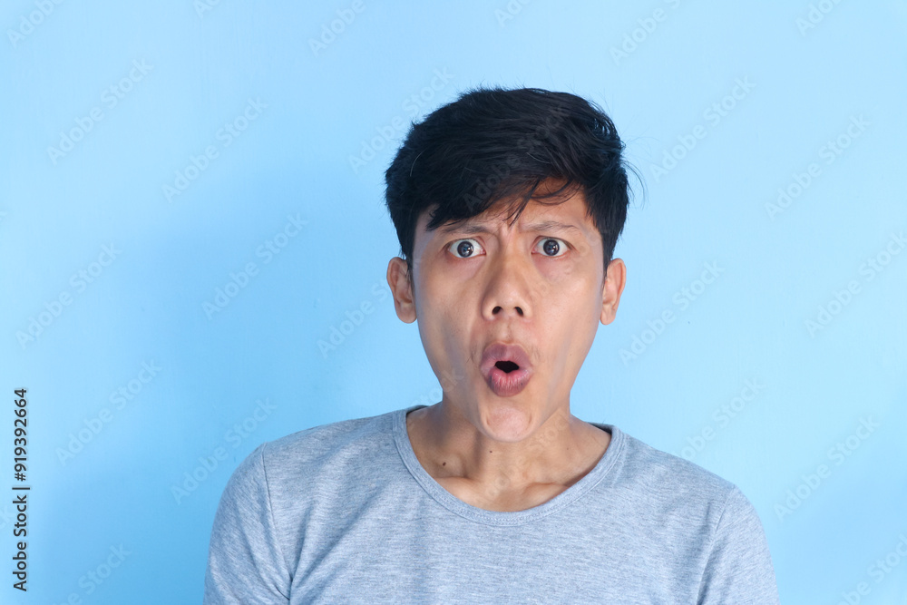 Shocked face of Asian young man in grey t-shirt on a isolated background. Shocked face of Asian young man in grey t-shirt on a isolated background.