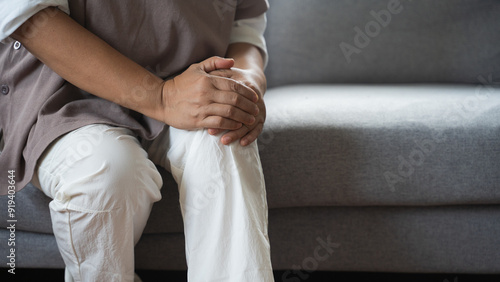 Close up hand of overweight woman arthritis sitting joint ache, sore cramp or sprain tendon in leg on sofa at home, Osteoarthritis chronic disease of body problem from trauma, Health care of knee pain