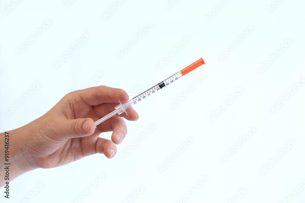 Insulin syringe. A woman's hand holds a syringe on a white background, close-up. Insulin syringe for diabetes. Diabetes treatment. Medicine and health concept Insulin syringe. A woman's hand holds a syringe on a white background, close-up. Insulin syringe for diabetes. Diabetes treatment. Medicine and health concept