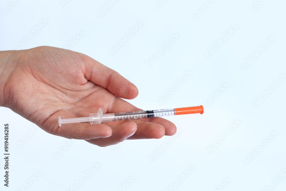 Insulin syringe. A woman's hand holds a syringe on a white background, close-up. Insulin syringe for diabetes. Diabetes treatment. Medicine and health concept Insulin syringe. A woman's hand holds a syringe on a white background, close-up. Insulin syringe for diabetes. Diabetes treatment. Medicine and health concept