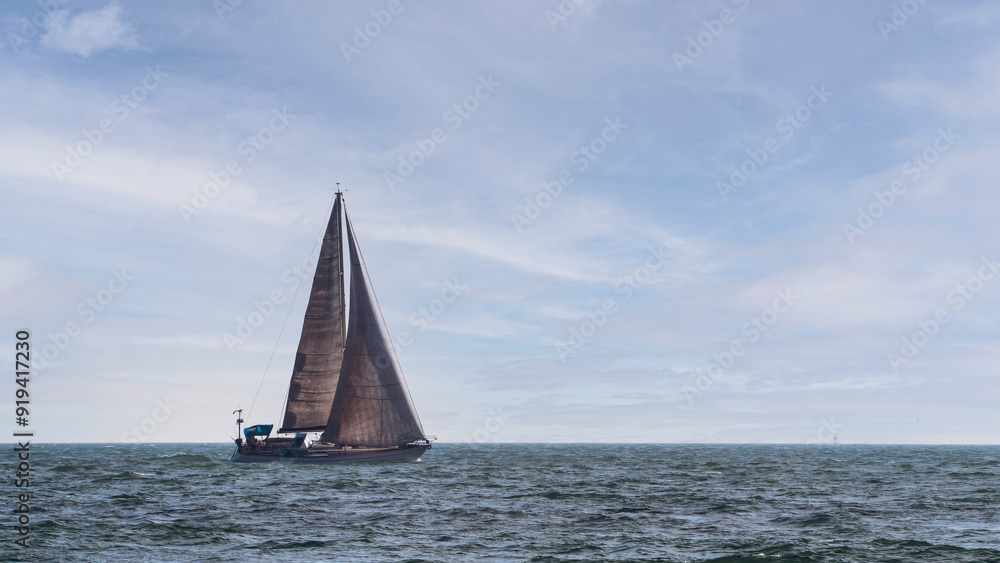 Obraz premium A yacht in the open sea against a background of blue sky.