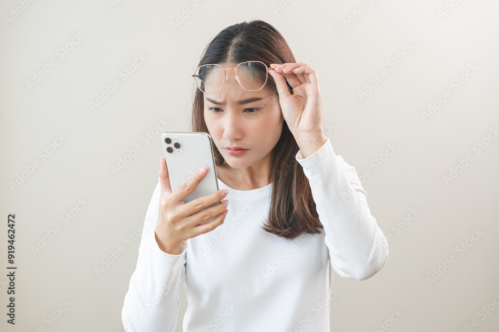 Presbyopia, Hyperopia middle aged asian woman holding eyeglasses problem with vision blurred ,trying to read text message from smart mobile phone screen, eye disease of old, eyesight farsightedness. Presbyopia, Hyperopia middle aged asian woman holding eyeglasses problem with vision blurred ,trying to read text message from smart mobile phone screen, eye disease of old, eyesight farsightedness.