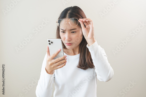 Presbyopia, Hyperopia middle aged asian woman holding eyeglasses problem with vision blurred ,trying to read text message from smart mobile phone screen, eye disease of old, eyesight farsightedness.