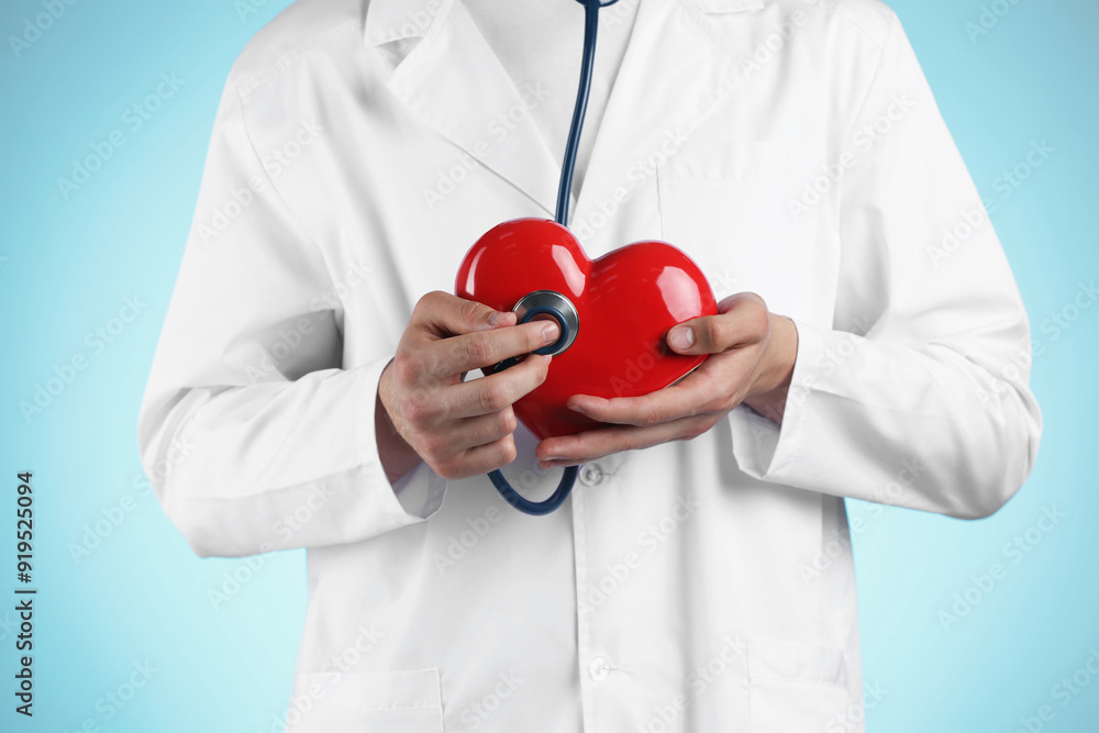 Doctor with stethoscope and red heart on light blue background, closeup Doctor with stethoscope and red heart on light blue background, closeup
