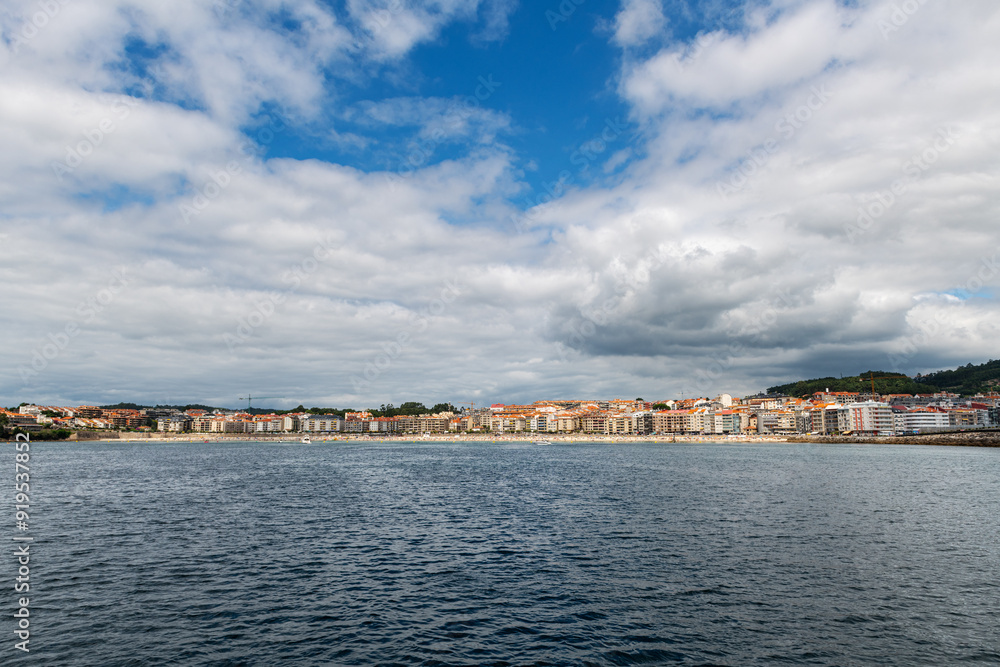 Panorama view of Sanxenxo and Silgar beach as seen from the sea on a cloudy Summer day in the Rias Baixas in Galicia, Spain. Panorama view of Sanxenxo and Silgar beach as seen from the sea on a cloudy Summer day in the Rias Baixas in Galicia, Spain.
