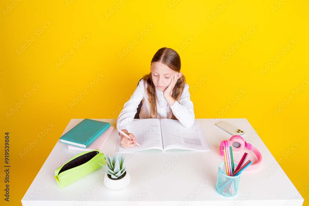 Photo portrait of cute little schoolgirl do boring homework dressed stylish uniform isolated on yellow color background Photo portrait of cute little schoolgirl do boring homework dressed stylish uniform isolated on yellow color background