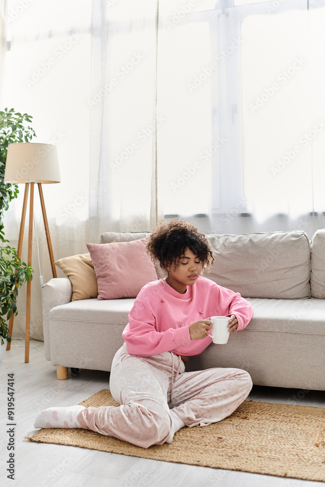 A young woman relaxes on the floor with a cup, soaking in the comfort of her home. A young woman relaxes on the floor with a cup, soaking in the comfort of her home.