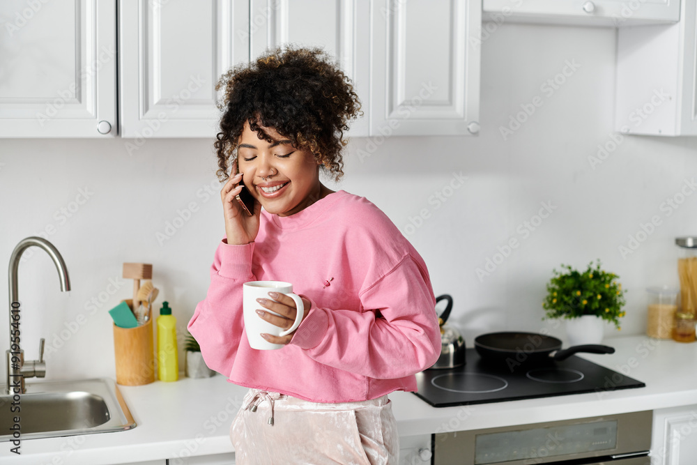 Smiling woman chats on the phone while holding a warm mug at home. Smiling woman chats on the phone while holding a warm mug at home.