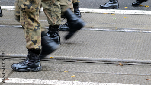 Generic army soldiers marching through the street in green camo uniforms and black boots, copy space background, group of people, news shot Motion, movement infantry training parade operations concept